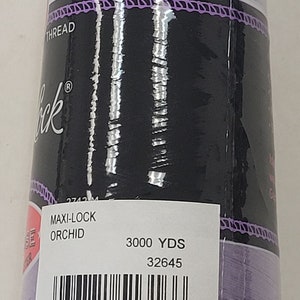 Peut inclure: Une bobine de fil Maxi-Lock de couleur orchidée. La bobine est étiquetée avec 3000 yards et le numéro 32645. Le code-barres est 0 36771 51316 6.