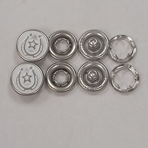 May include: A set of eight silver snap fasteners with a horseshoe and star design. The fasteners are in two sizes, with four larger fasteners and four smaller fasteners.