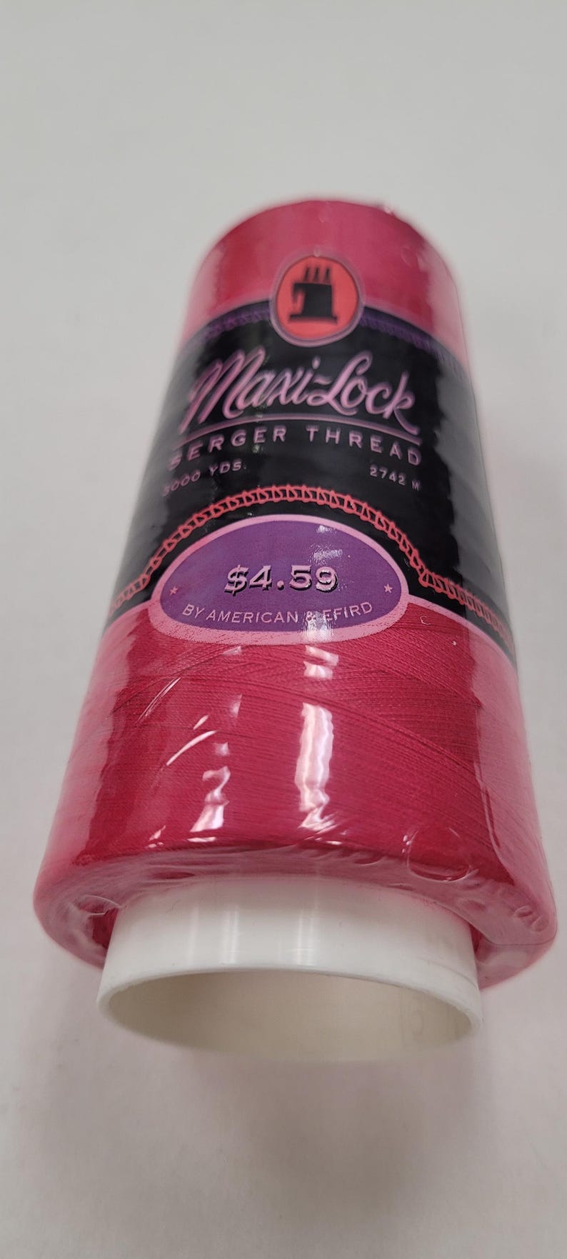 May include: A spool of pink Maxi-Lock serger thread by American & Efird. The spool is labeled with the text "Maxi-Lock Serger Thread", "3000 YDS", "2742 W", "$4.59", and "By American & Efird".