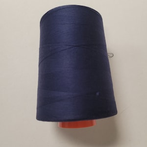 May include: A spool of dark blue thread.