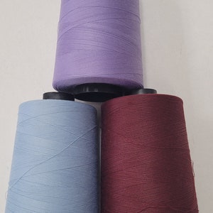 May include: Three spools of thread, one purple, one blue, and one maroon.