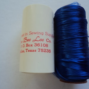 May include: A spool of bright blue thread with a white label that reads "est in Sewing Supply Bee Lee Co. P.O. Box 36108 llas, Texas 75235"