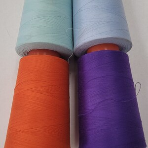 May include: Four spools of thread, two light blue, one orange, and one purple.