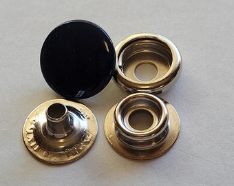 以下が含まれることがあります： 黒と銀の4つのスナップファスナーのセット。ファスナーは金属製で、丸い形をしています。黒いファスナーはキャップで、銀色のファスナーはソケット、スタッド、ベースです。