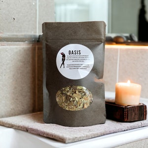 Peut inclure: Un sac en papier brun avec une étiquette blanche indiquant "OASIS" et une description du mélange balkanique traditionnel à l'intérieur. Le sac a une fenêtre transparente montrant les herbes séchées à l'intérieur.