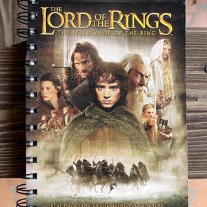May include: A spiral bound notebook with a cover featuring the Lord of the Rings: The Fellowship of the Ring movie poster. The cover features a close-up of Frodo Baggins, Gandalf the Grey, Aragorn, and other characters from the movie. The text "REAL MAGIC! ONE OF THE BEST FILMS OF THE YEAR." is printed at the bottom of the cover.