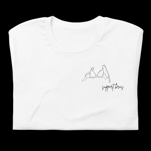 May include: White t-shirt with a black line drawing of a bra and the text "support bras".