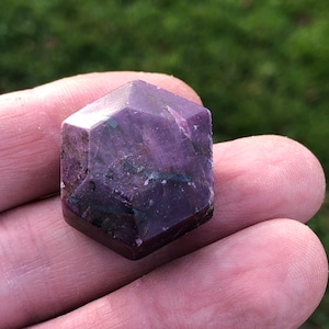 Könnte beinhalten: Ein violetter, facettierter, sechseckiger Kristall mit einer rauen, natürlichen Textur.