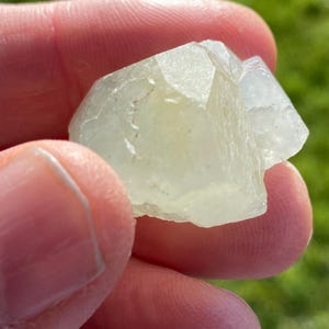 May include: A translucent, white, crystal-like rock with a rough, faceted surface.
