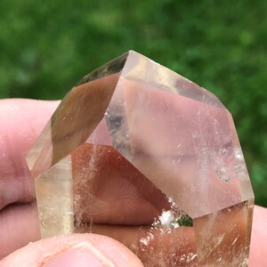 May include: A clear, faceted, quartz crystal with a light golden hue. The crystal is shaped like a pyramid with a flat base.