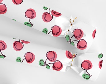May include: Five white paper party crackers with a red cherry pattern. The crackers are tied with gold string.