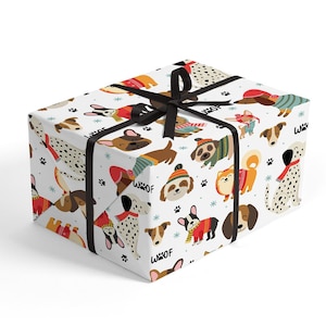 May include: A wrapped gift box featuring a white background with a repeating pattern of various dog breeds in sweaters and hats. The box is tied with a black ribbon. The word "Woof" is printed on the wrapping paper.