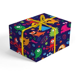 Pode incluir: Um papel de embrulho azul com uma fita amarela. O papel de embrulho apresenta um padrão de monstros de desenhos animados coloridos, estrelas e círculos.