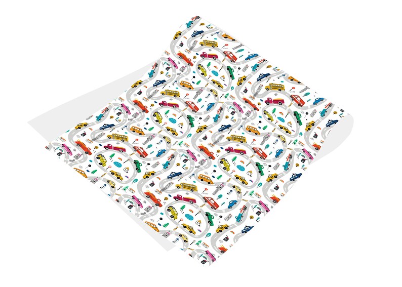 May include: A white wrapping paper with a repeating pattern of colorful cars, trucks, and buses driving on winding roads. The pattern includes small details like trees, streetlights, and puddles.
