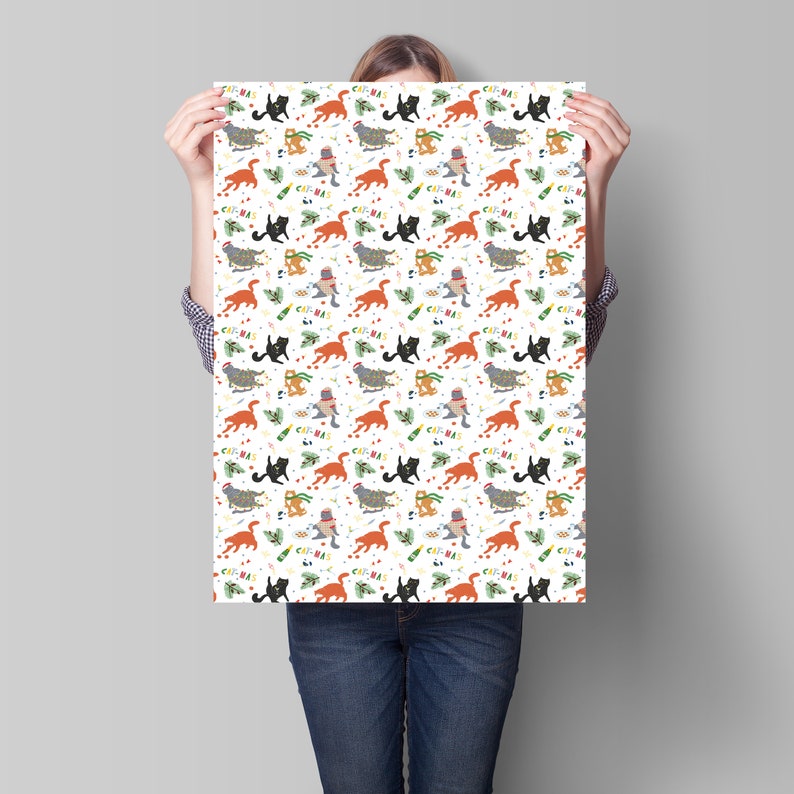 Puede incluir: Papel de regalo blanco con un patr&oacute;n repetitivo de gatos con gorros de Pap&aacute; Noel y sosteniendo botellas de champ&aacute;n. El texto "Cat-mas" se repite en todo el patr&oacute;n.