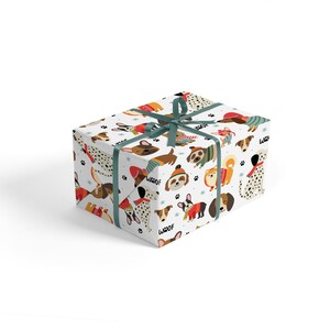May include: A wrapped gift box featuring a white background with a repeating pattern of various dog breeds in winter attire. The dogs are wearing sweaters, hats, and scarves. The box is tied with a teal ribbon.