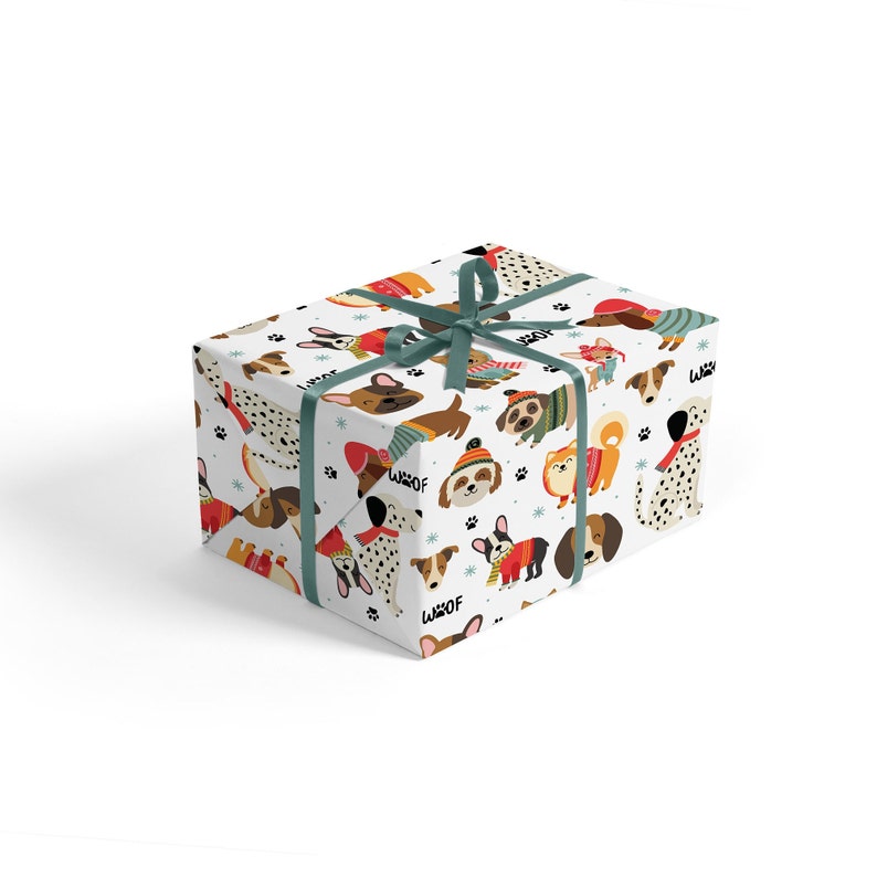May include: A wrapped gift box featuring a white background with a repeating pattern of various dog breeds in winter attire. The dogs are wearing sweaters, hats, and scarves. The box is tied with a teal ribbon.