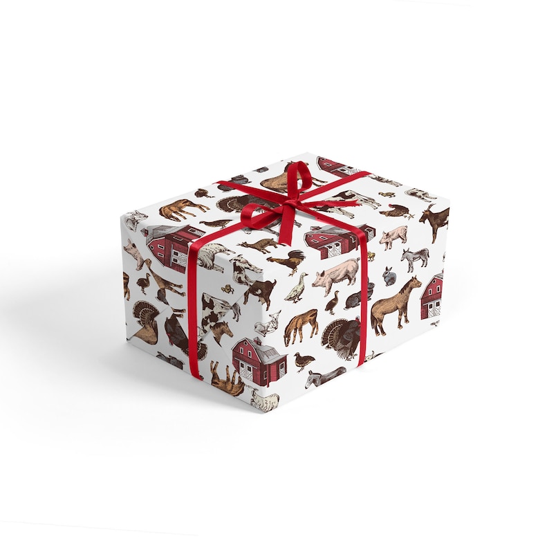 May include: A white gift box with a red ribbon and a farm animal print. The print features cows, pigs, chickens, horses, and a red barn.