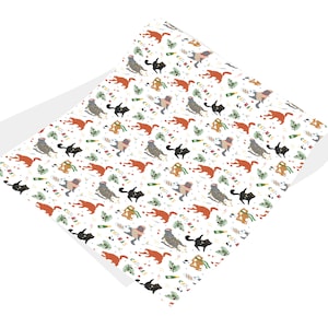 Puede incluir: Papel de regalo blanco con un patr&oacute;n repetitivo de gatos con gorros de Pap&aacute; Noel y sosteniendo copas de champ&aacute;n. Los gatos son naranja, gris y negro. El fondo es blanco con hojas de acebo verdes y bayas rojas.
