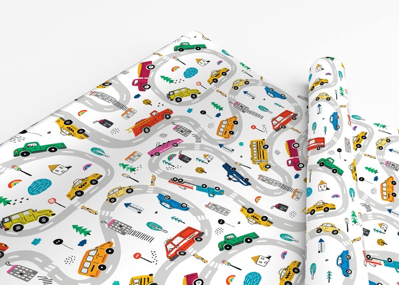 May include: White wrapping paper with a repeating pattern of colorful cars, trucks, buses, and taxis driving on winding gray roads. The design includes small details like trees, houses, and rainbows.