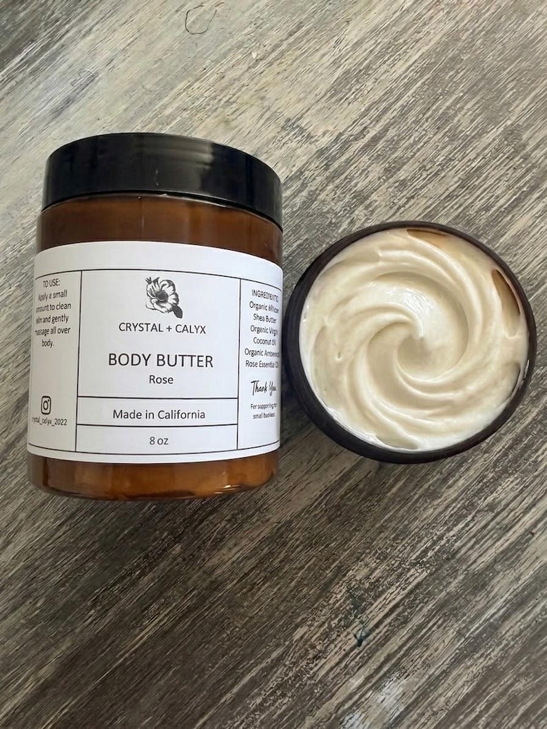 May include: An 8 oz amber plastic jar of Crystal + Calyx Rose body butter with a black lid and a white label featuring text, alongside an open jar revealing a swirled, creamy white substance. The label lists ingredients and usage instructions.