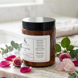 May include: An 8 oz amber plastic jar of Crystal + Calyx Rose Body Butter with a black lid. The white label lists ingredients including organic African shea butter, organic virgin coconut oil, organic arrowroot powder, and rose essential oil.