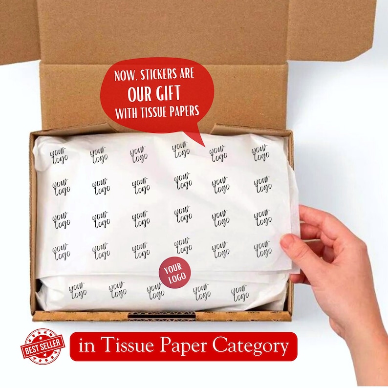 May include: A brown cardboard box with a white tissue paper liner. The tissue paper is printed with the words "your logo" in a handwritten font. The box is open and the tissue paper is being pulled out. The text "NOW. STICKERS ARE OUR GIFT WITH TISSUE PAPERS" is written in red on a white speech bubble. The text "YOUR LOGO" is written in red on a white circle. The text "BEST SELLER" is written in red on a white starburst. The text "in Tissue Paper Category" is written in red on a white banner.