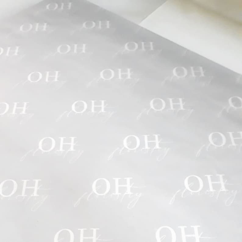 May include: A sheet of light gray wrapping paper with a repeating pattern of the letters "OH" in white.