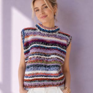 Op de afbeelding: Een mouwloos gebreid vest met een horizontaal gestreept patroon in tinten paars, wit, blauw, oranje en zwart. Het kledingstuk heeft een hoge mock-hals en een dikke, grove breistructuur met zichtbare garenvariaties door het hele ontwerp heen.