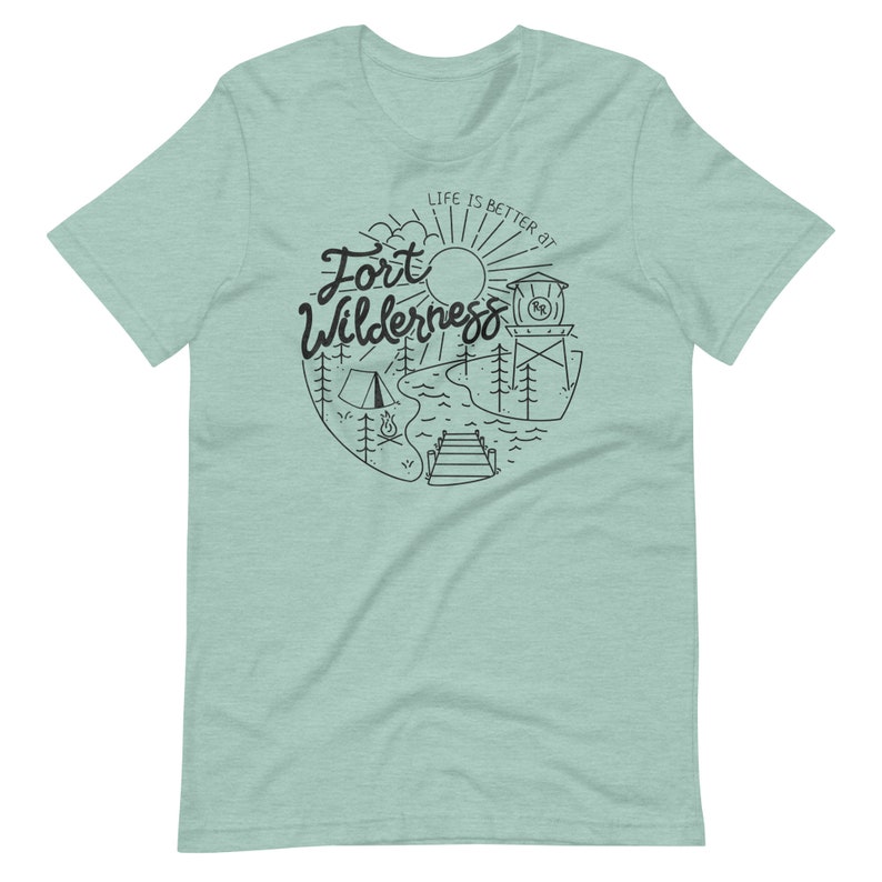 May include: A light blue t-shirt with a black graphic design of a sun, trees, a lake, a dock, a campfire, and a tent. The text "Life is better at Fort Wilderness" is written in a cursive font.