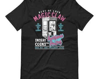 May include: A black t-shirt with a vintage-style illustration of a claw machine with the text "Best of Luck Magic Claw" and "Insert Coins for Awesome Prizes".