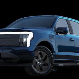 May include: A blue Ford F-150 Lightning electric pickup truck. The truck has black wheels, a black front grill, and white LED headlights. The Ford logo is visible on the front.