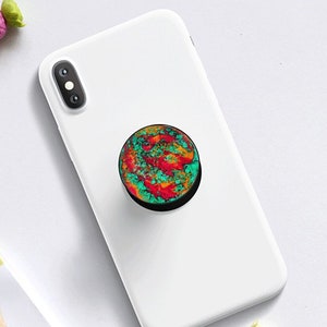 May include: A colourful phone grip with a swirling pattern of red, orange, yellow, green, and blue. The grip is black and has a circular shape.