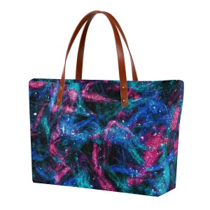 May include: A large tote bag with brown leather handles and a galaxy print. The print features swirling blue, pink, and teal colors with white glitter accents.