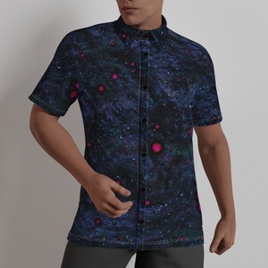 Puede incluir: Una camisa de manga corta con botones, fondo azul oscuro y estampado de galaxia con detalles en rosa y morado.