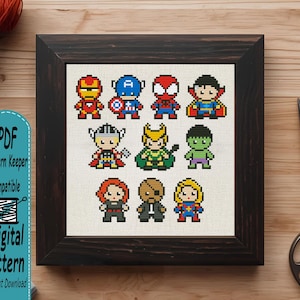 May include: A framed cross-stitch pattern featuring eleven pixel-art style superhero characters arranged in three rows. The characters include Iron Man, Captain America, Spider-Man, Doctor Strange, Thor, Loki, Hulk, Black Widow, Nick Fury, and Captain Marvel.