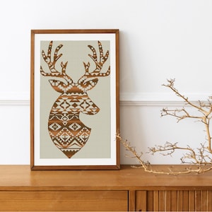 May include: A framed print of a brown and white geometric deer head silhouette on a beige background.