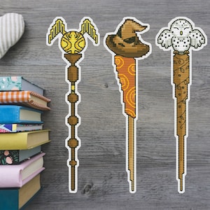 Puede incluir: Tres marcapáginas con temática de Harry Potter con diferentes diseños. El primer marcapáginas presenta una snitch dorada con alas, el segundo marcapáginas presenta un sombrero de selección marrón y el tercer marcapáginas presenta un búho blanco.