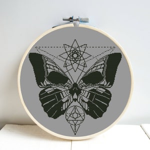May include: A black and white geometric design of a butterfly with a skull-like head, surrounded by a starburst and a triangle with a circle in the center.