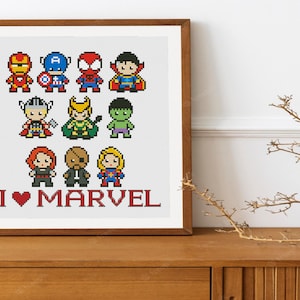 Peut inclure: Un dessin de point de croix encadré représentant une collection de personnages de super-héros Marvel dans un style pixel art. Les personnages incluent Iron Man, Captain America, Spider-Man, Doctor Strange, Thor, Loki, Hulk, Black Widow, Hawkeye et Captain Marvel. Le texte "I ♥ MARVEL" est affiché sous les personnages.
