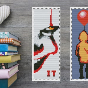Può includere: Due modelli di segnalibro a punto croce con personaggi del romanzo horror "IT". Il primo segnalibro presenta un'illustrazione rossa e nera del volto di Pennywise il clown. Il secondo segnalibro presenta una silhouette gialla di un bambino che tiene un palloncino rosso su uno sfondo blu. Il testo "IT" è stampato in rosso sul primo segnalibro.