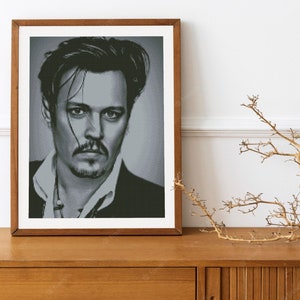 May include: A black and white portrait of a man with dark hair and a goatee. He is wearing a suit jacket and a white shirt. The portrait is framed in a wooden frame.