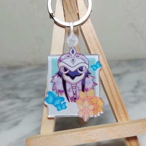 Peut inclure: Un porte-clés en acrylique transparent représentant un personnage de dessin animé avec un masque blanc et des cheveux violets. Le personnage est entouré de papillons bleus et de fleurs jaunes. Le porte-clés est attaché à un anneau en métal argenté.