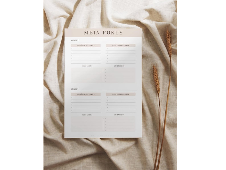 May include: A printable planner page with the title "Mein Fokus" in German. The page is divided into four sections, each with the heading "Mein Ziel" and space for writing down goals and action steps. The page is designed in a minimalist style with a light beige background.