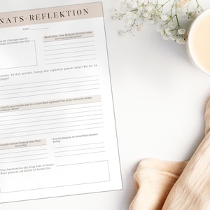 May include: A printable monthly reflection worksheet in German with the title "Monats-Reflektion" and prompts for reflection on the month, including favorite moments, challenging situations, and self-care practices.