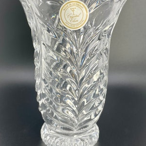 May include: A clear glass vase with a 24% lead crystal label. The vase has a scalloped rim and a textured design.