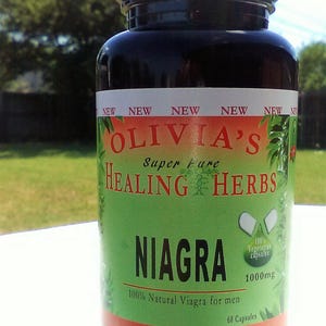 Op de afbeelding: Een zwarte fles met een groen en rood etiket waarop staat "Olivia's Super Pure Healing Herbs Niagra 100% Natural Viagra for men 1000mg 60 Capsules". Het etiket bevat ook de tekst "100% Vegetarian Capsules".