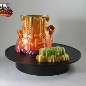 May include: A 3D printed, multi-colored backpack with a smaller, green backpack attached to the side. The larger backpack has a detailed design with straps and buckles. The smaller backpack has a simple design with a single strap. Both backpacks are on a black circular base.