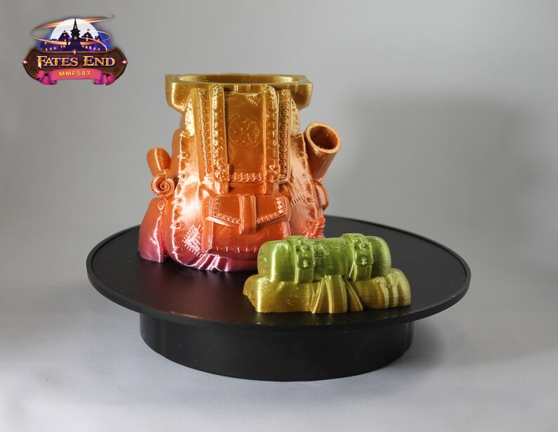 May include: A 3D printed, multi-colored backpack with a smaller, green backpack attached to the side. The larger backpack has a detailed design with straps and buckles. The smaller backpack has a simple design with a single strap. Both backpacks are on a black circular base.