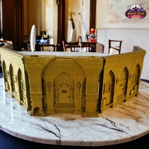 Può includere: Un modello 3D stampato di un edificio con una facciata in pietra gialla. L'edificio ha un grande portale ad arco e diverse finestre. Il modello è posto su una superficie di marmo.